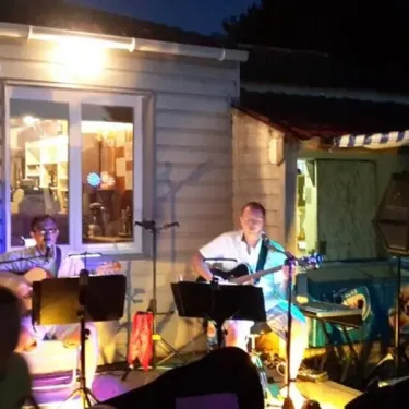 Camping Le Parc de la Grève : spectacle musical nocturne devant une cabane.