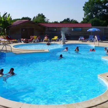 Piscine avec enfants nageant, chaises longues et cabane en bois au Camping Le Parc de la Grève