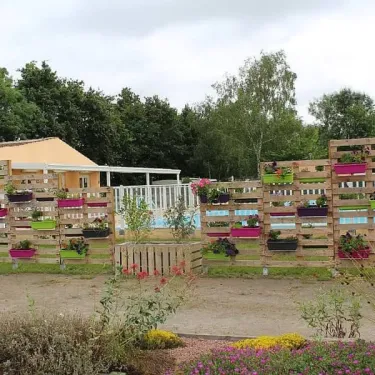 Panneaux en palette décoratifs avec plantes colorées autour du camping