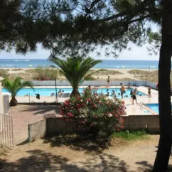Piscine entourée d'arbres avec vue sur la mer depuis le Camping Olmello Plage
