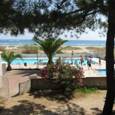 Piscine entourée d'arbres avec vue sur la mer depuis le Camping Olmello Plage