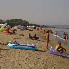 Camping Olmello Plage - plage animée avec parasols, personnes dans l'eau et sur le sable
