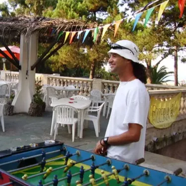 Homme jouant au football sur table dans un espace extérieur du Camping Olmello Plage