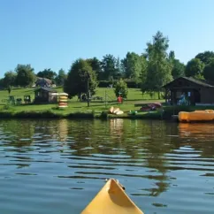 Vue depuis un kayak jaune sur un lac avec des cabanes et une aire de repos.