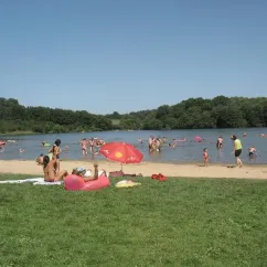 Camping de la Borde : plage animée avec des visiteurs dans l'eau et sur le sable sous un ciel bleu.