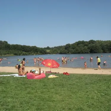 Camping de la Borde : plage animée avec des visiteurs dans l'eau et sur le sable sous un ciel bleu.