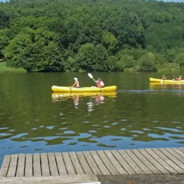 Deux personnes en kayak jaune sur un lac entouré de forêt dense.