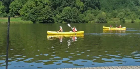 Deux personnes en kayak jaune sur un lac entouré de forêt dense.