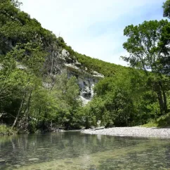 Rivière paisible entourée de falaises et de forêt dense au Camping Le Médieval.