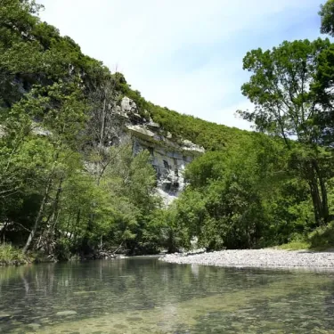 Rivière paisible entourée de falaises et de forêt dense au Camping Le Médieval.