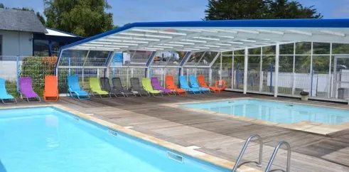 Piscine couverte avec chaises longues colorées au Camping La Mer Blanche