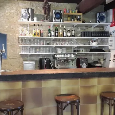 Bar avec étagères de boissons, cafetière et tabourets au Camping Les Rives du Céou
