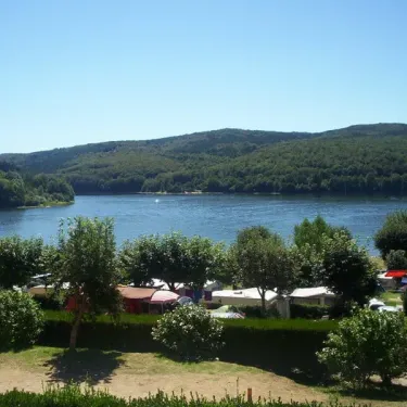 Ville de camping avec caravanes et montagnes en arrière-plan au Camping Le Rouquié du Lac