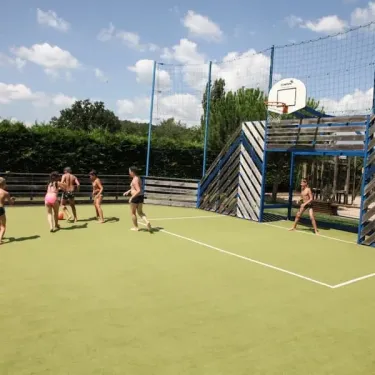 Enfants jouent au basket-ball sur une cour extérieure au Camping La Sole.