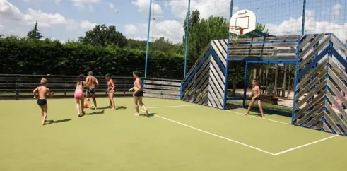 Enfants jouent au basket-ball sur une cour extérieure au Camping La Sole.
