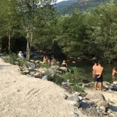 Groupes de personnes se baignent dans une rivière entourée de forêt et de montagnes au Camping Les Templiers.