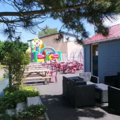 Zone de jeux en plein air avec manège gonflable et tables de pique-nique au Camping Vitamin