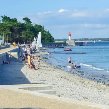 Plage du camping Le Bois d'Amour - 29 avec des personnes et un phare en arrière-plan