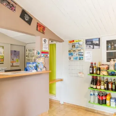 Comptoir de vente du Camping le Beauchêne avec produits et boissons sur étagères