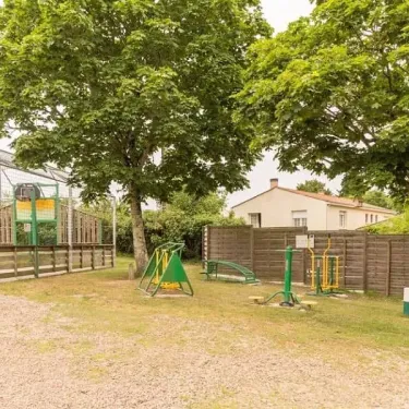 Camping le Beauchêne : aire de jeux extérieure avec équipements verts et arbres