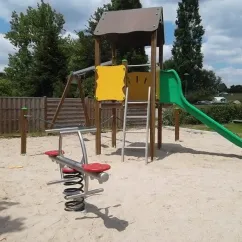 Parc d'activités pour enfants avec toboggan vert et balançoire à ressort au Camping le Beauchêne