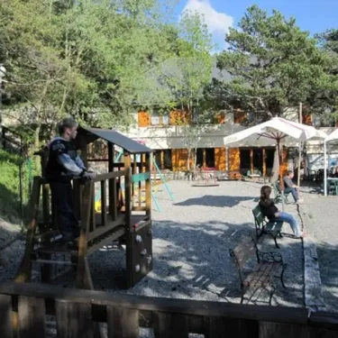 Enfant sur une structure de jeu dans le camping Le Champ Long, avec un espace détente et parasols.