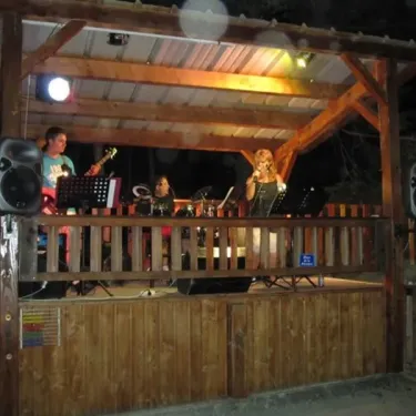 Performance musicale nocturne sous une estrade en bois au Camping Le Champ Long.