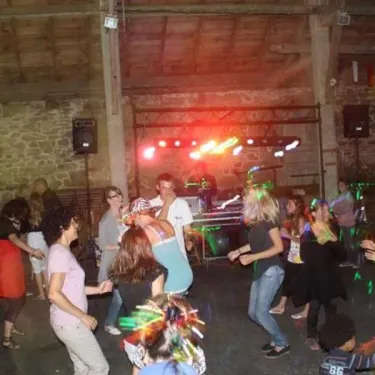Fête nocturne au Camping Kerscolper avec musique, lumières et danse dans une salle en pierre.