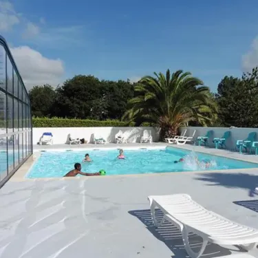 Piscine avec enfants jouant, chaises longues et palmier au Camping Kerscolper