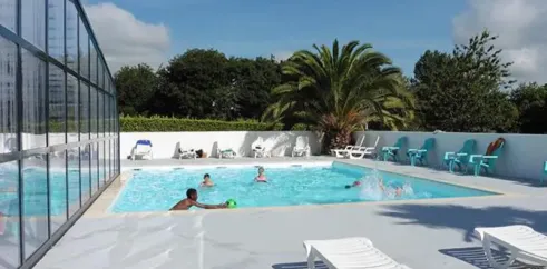 Piscine avec enfants jouant, chaises longues et palmier au Camping Kerscolper