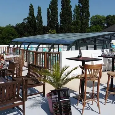 Terrasse avec tables, chaises et pergola au Camping Kerscolper