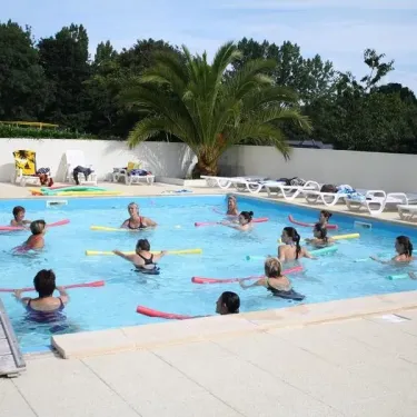 Camping Kerscolper : groupe faisant de l'eau avec des bâtonnets colorés dans une piscine extérieure.