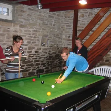 Quatre personnes jouent au billard dans une salle en pierre, Camping du Manoir de Penn Ar Ster