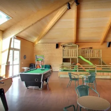 Salle de jeux en bois avec billard, football sur table et toboggan pour enfants au Camping Les Trois Sources