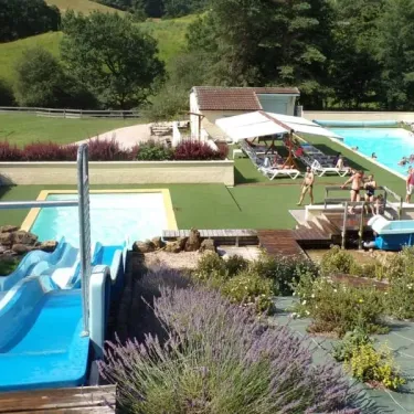 Piscine animée avec chaises longues et toboggan bleu au Camping Les Trois Sources.