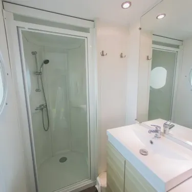 Salle de bain avec douche, lavabo et miroir - Mobil Home Confort+ - La Ferme