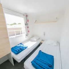 Chambre du Mobil Home Confort+ 3 Chambres 6 Personnes - La Ferme avec deux lits et draps bleus