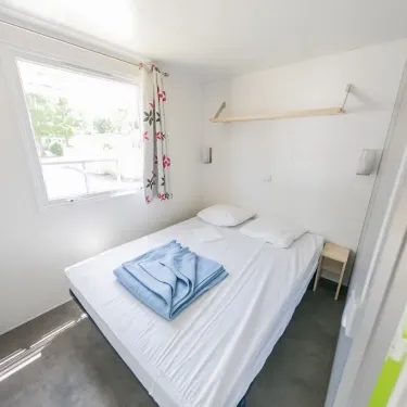Chambre du Mobil Home Confort+ 3 Chambres 6 Personnes - La Ferme avec lit double et drap bleu