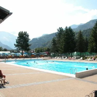 Piscine extérieure entourée de chaises longues et de pins, Camping de Samoëns