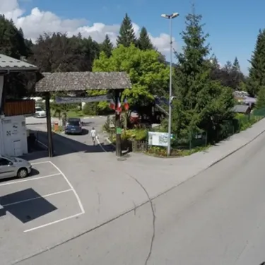 Entrée du Camping de Samoëns avec bâtiment, parking et forêt en arrière-plan.