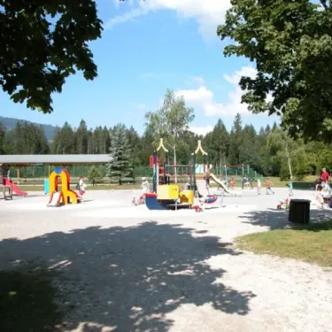 Camping de Samoëns : aire de jeux pour enfants avec toboggans, passerelles et arbres ombragés.