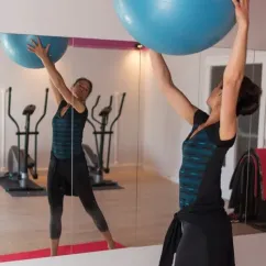 Femme pratiquant une séance d'entraînement avec ballon de yoga dans la salle de sport