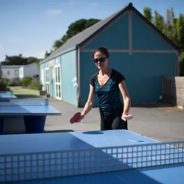 Une femme joue au ping-pong à Camping Emeraude.