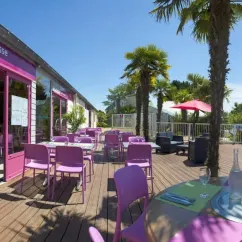 Terrasse du restaurant La Terrasse avec tables et chaises violettes sur bois