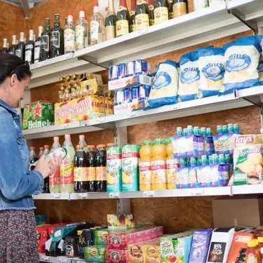 Une cliente choisit des boissons dans la boutique du camping Emeraude.