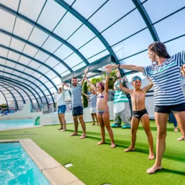 Groupes de personnes faisant des exercices collectifs près d'une piscine couverte au Camping Emeraude
