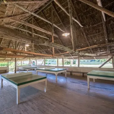 Salle de ping-pong en bois avec toit de chaume au Camping Le Gibanel
