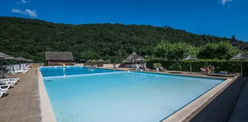 Piscine extérieure entourée de parasols et de chaises longues, Camping Le Gibanel