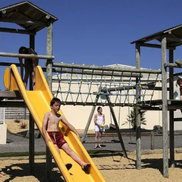 Enfants jouent sur une aire de jeux en bois au Camping Du Domaine de L'Auzance