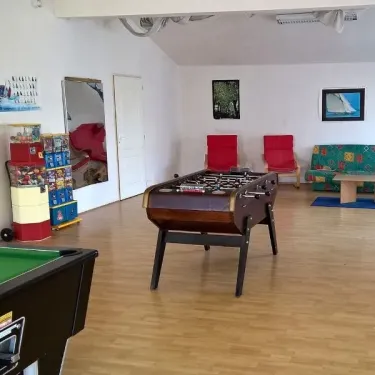 Salle de loisirs avec billard, table de football et canapé au Camping Du Domaine de L'Auzance